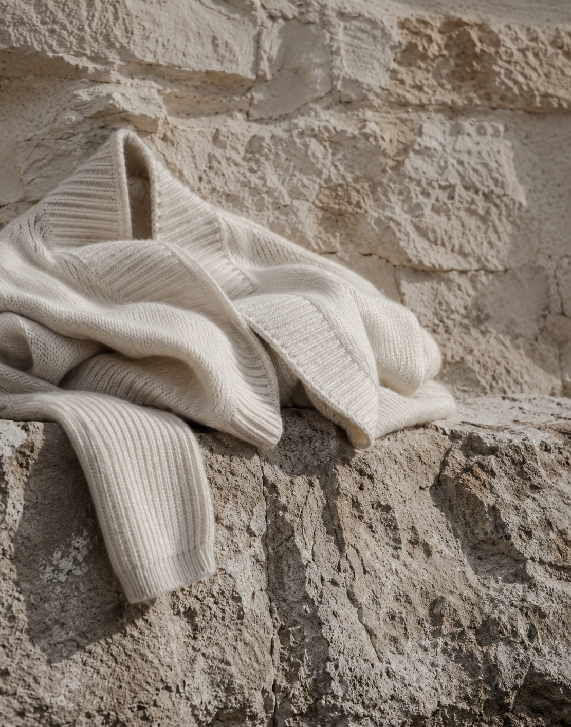 Undyed cashmere held against a stone wall in low winter sun